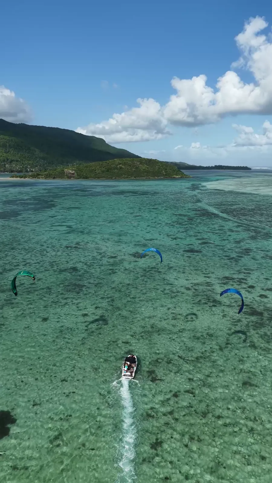 Aerial view of a school boat and several kites over the turquoise lagoon of Le Morne