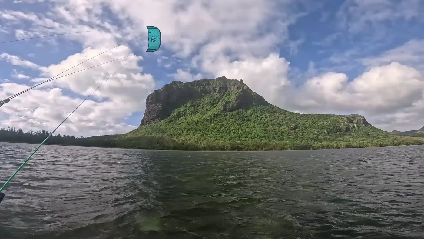 Water-level view of a kite flying in front of the Le Morne mountain